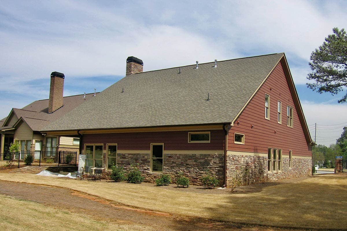 House plan exterior with stone and red siding, two chimneys, and hip and gable rooflines.