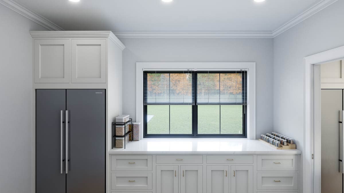 Kitchen interior with stainless steel refrigerator, white cabinetry, white marble countertop, and two windows with blinds overlooking a yard.