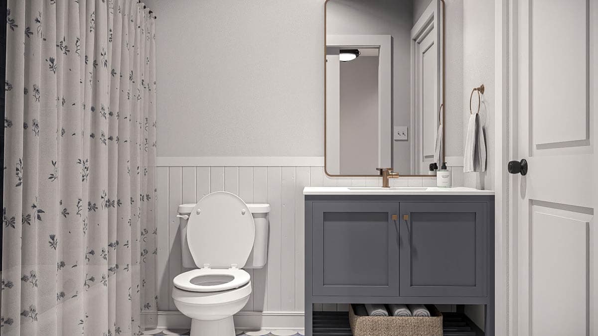 Bathroom with floral shower curtain, white toilet, gray vanity with brass pulls, and white paneled wainscoting.