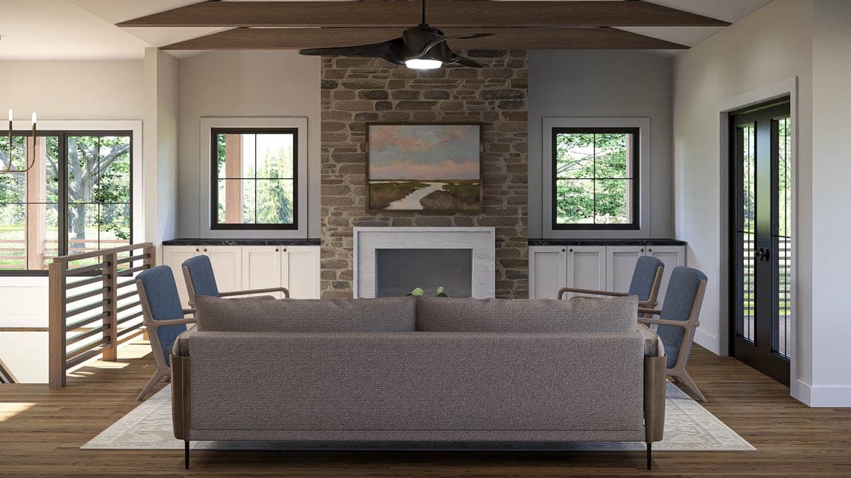 Great room with stone fireplace, vaulted ceiling with exposed beams, and large windows.