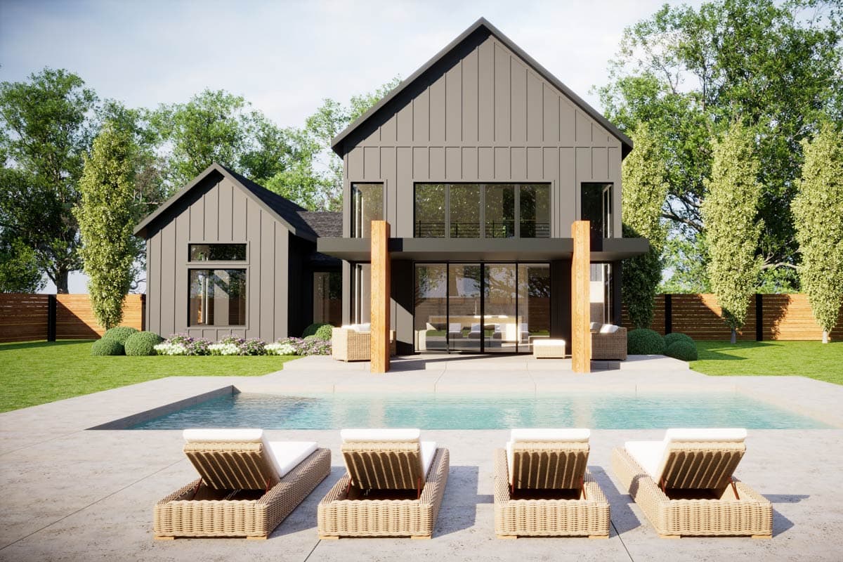Rear exterior view of contemporary gray house with large windows, pool, and trees.