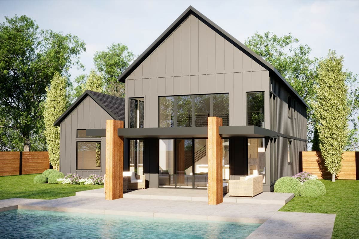 Rear exterior view of contemporary gray house with wooden posts and accent wall. Large windows and lush green yard.