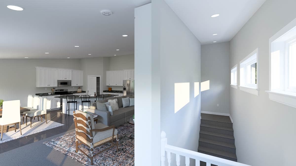 Interior view of open-concept living area with kitchen, dining, and seating space, adjacent to a staircase with windows.