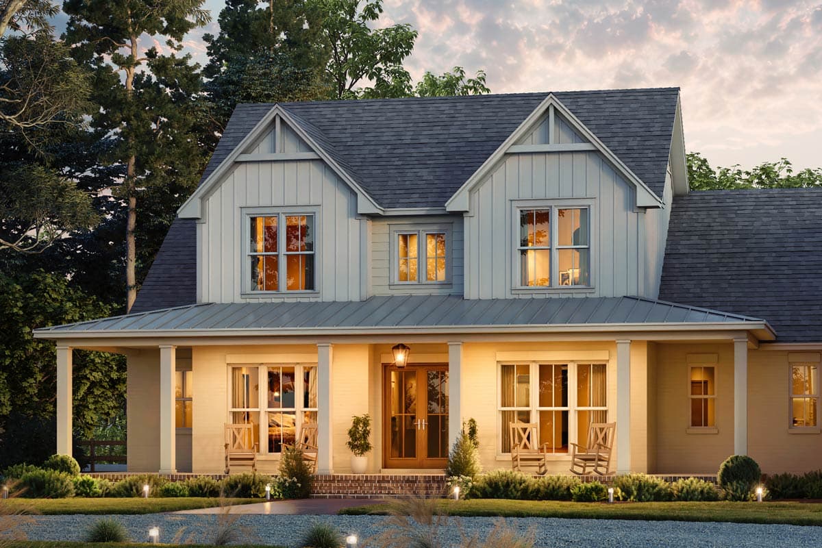 Exterior shot of a large, two-story house with a welcoming porch and glowing windows at dusk. Trees in the background.