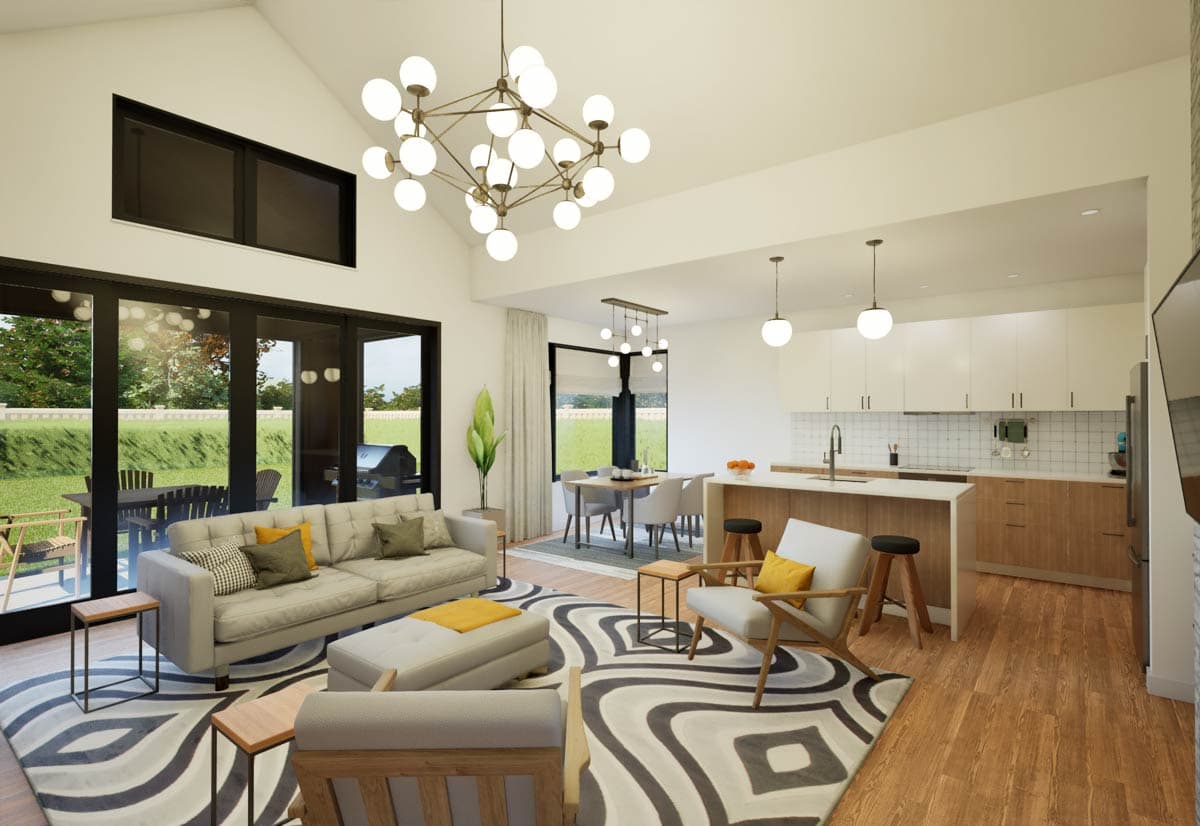 Open concept living space with vaulted ceiling, modern chandelier, kitchen island, and large windows overlooking outdoor patio.
