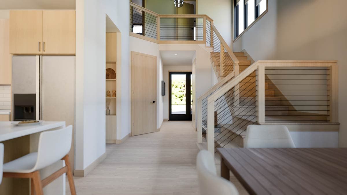 Interior view of modern house entry with light wood doors, staircase with horizontal cable railing, and kitchen area.