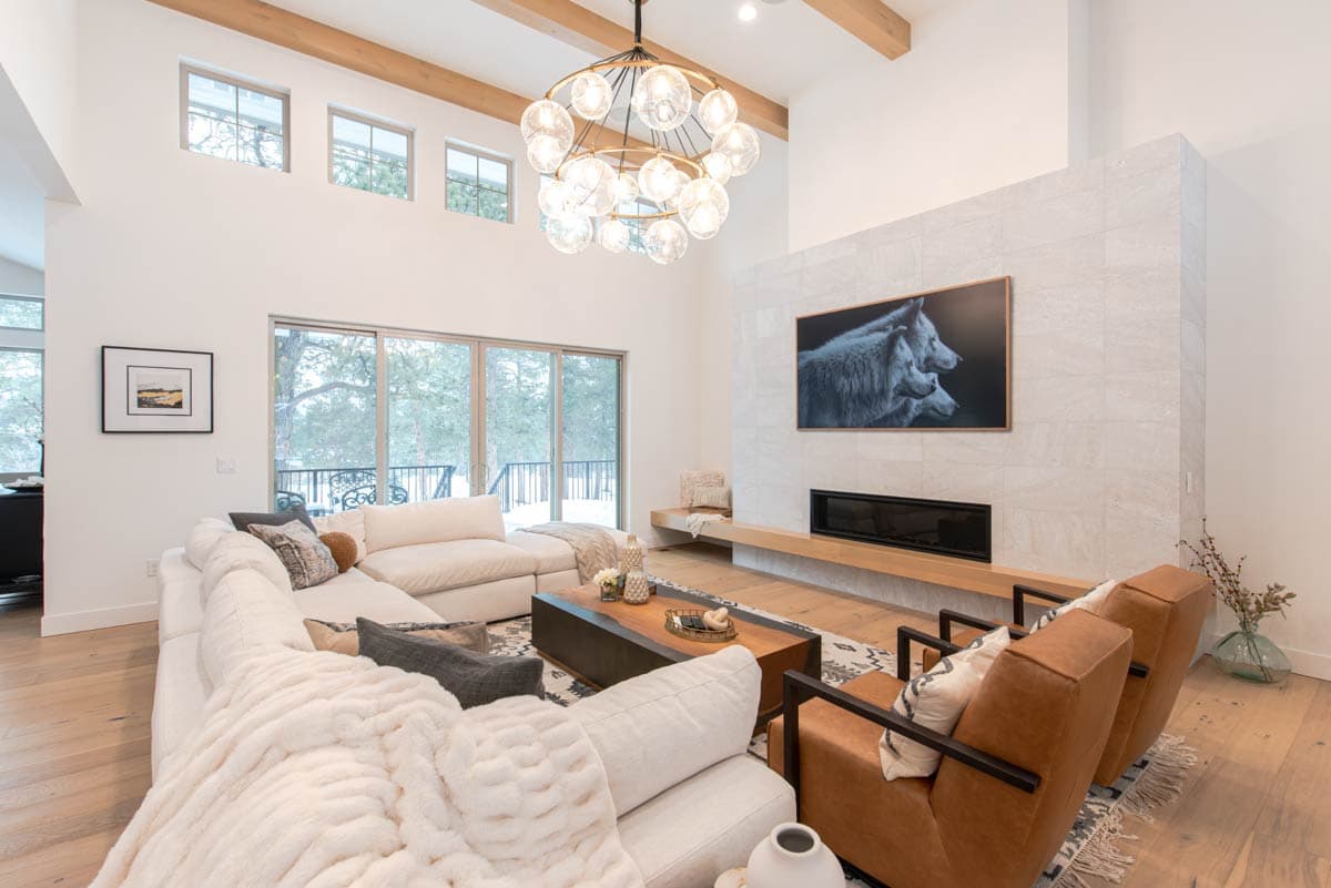 Great room with vaulted ceiling, exposed beams, large windows, fireplace, and sectional sofa.