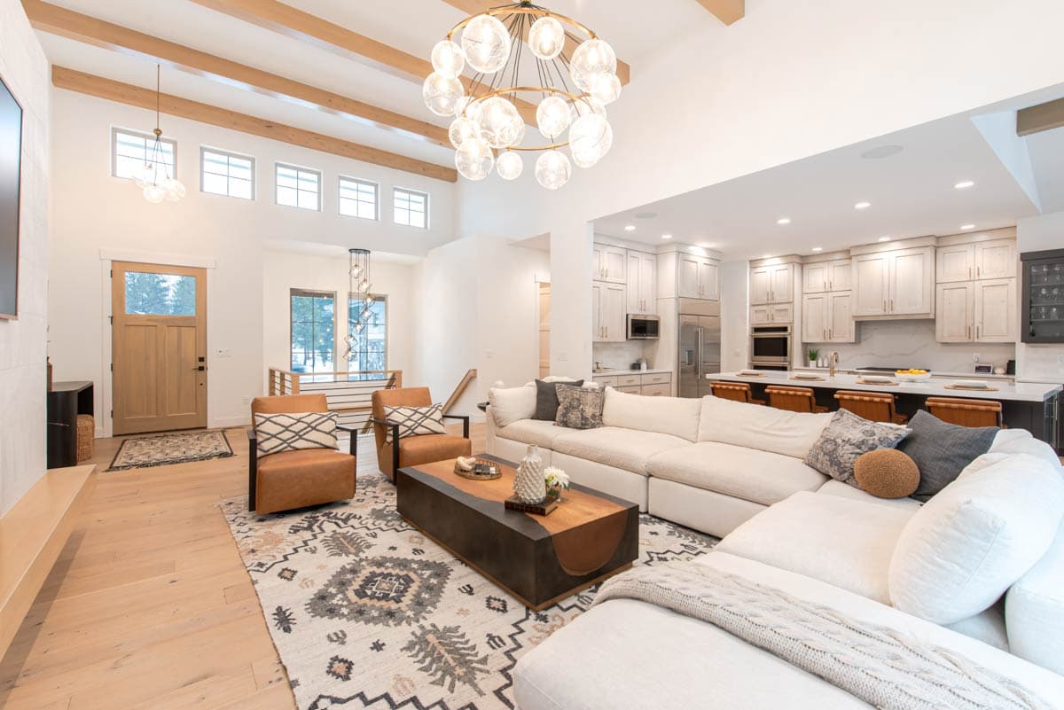 Open-concept living area and kitchen with vaulted ceiling, exposed beams, large sectional sofa, and island with seating.