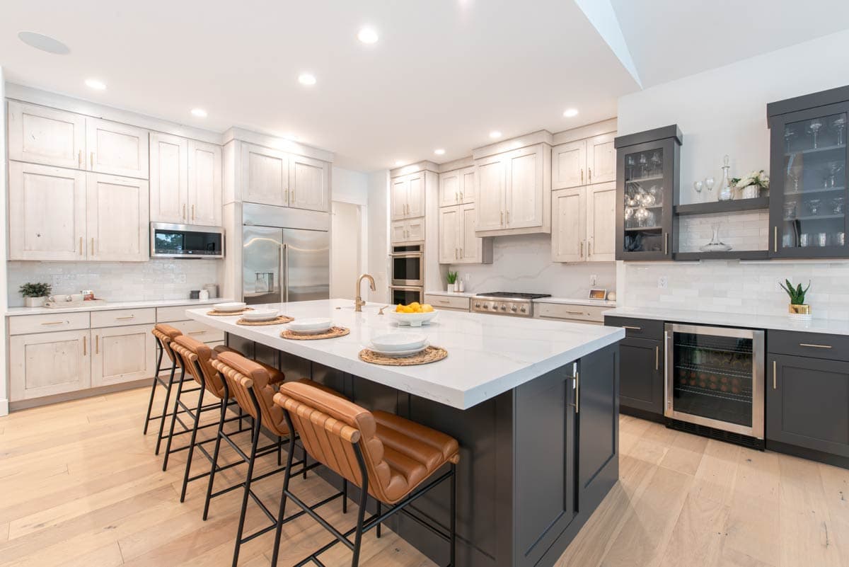 Contemporary kitchen with a large island, bar seating, stainless steel appliances, and two-tone cabinetry.