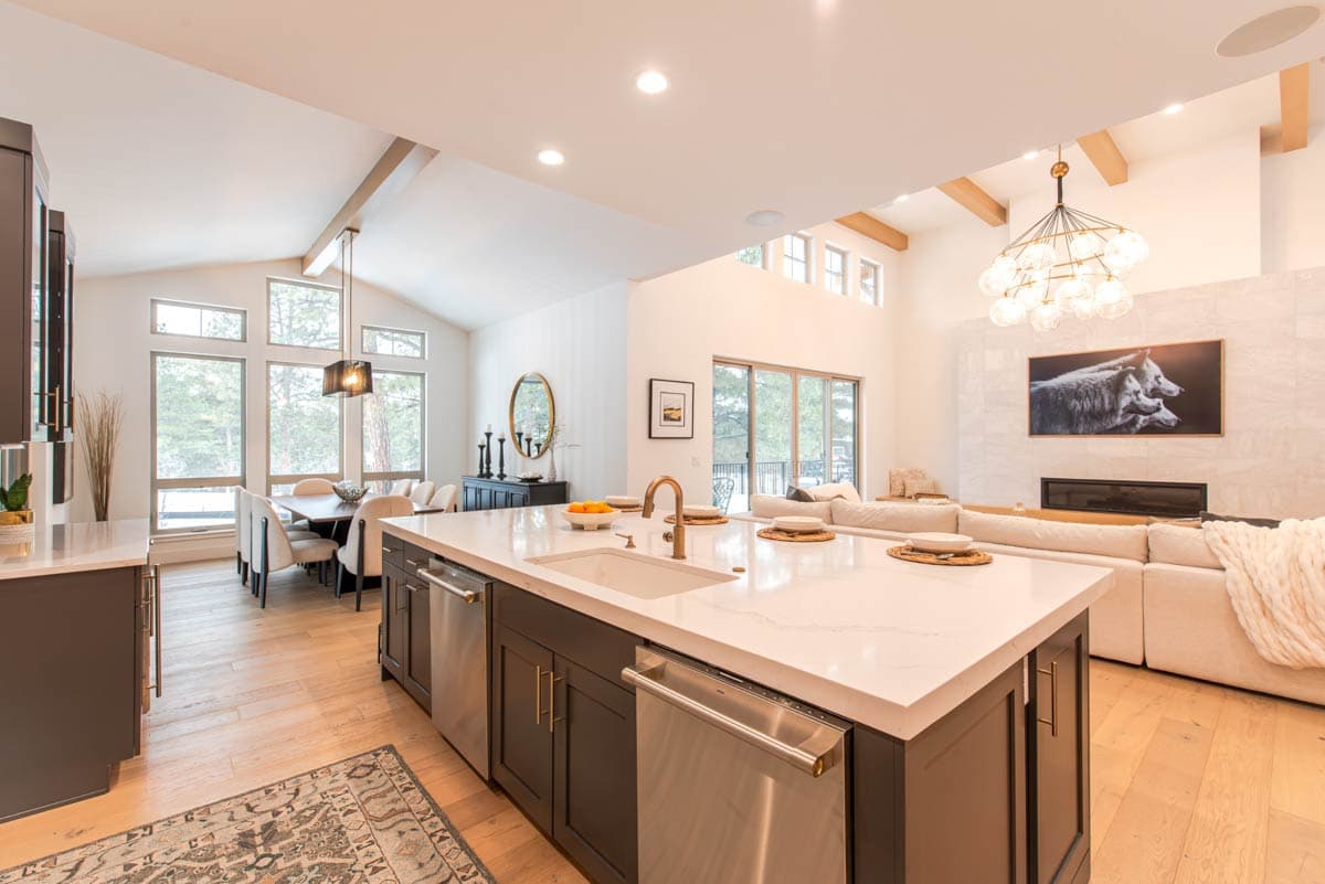Open concept kitchen with large island, dining area with vaulted ceiling, and living room with fireplace.