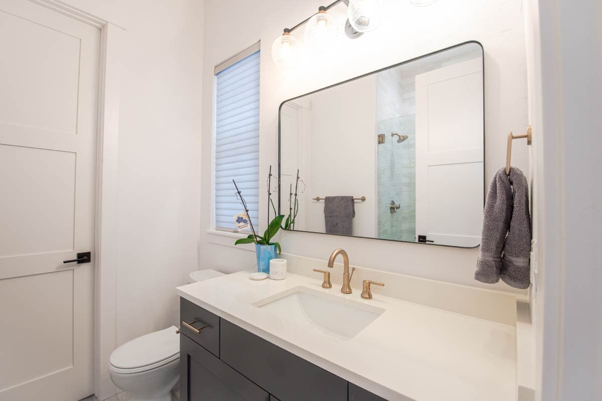 Bathroom with vanity, sink, toilet, shower, and modern lighting.