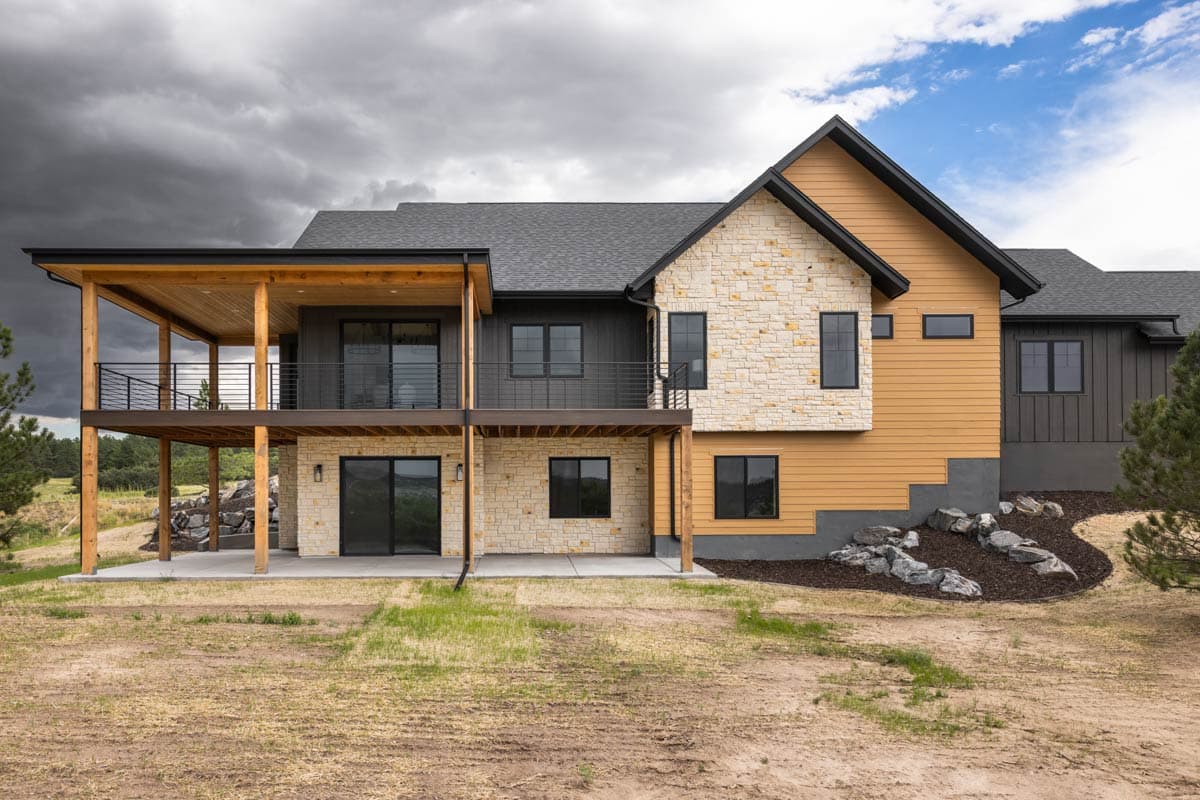 House plan exterior with stone and wood siding, covered deck, and multiple gables.