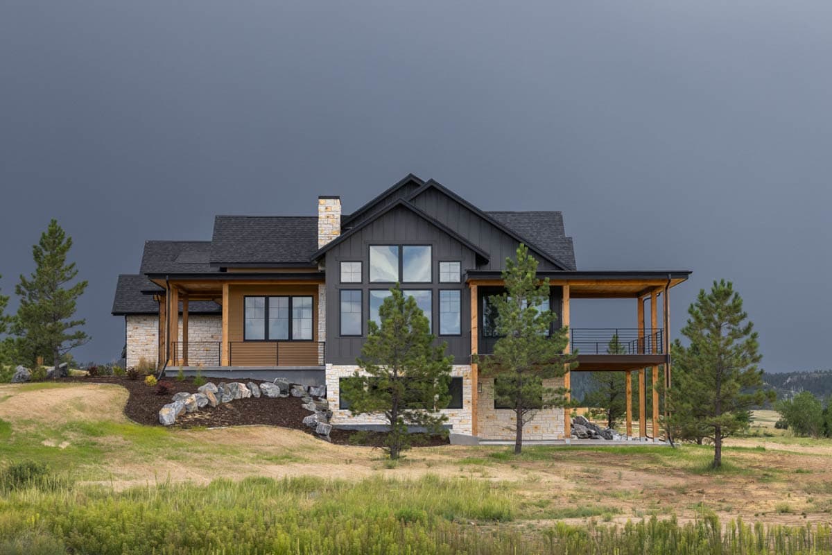 Modern house plan exterior with stone and wood facade, large windows, gabled roof, and covered balcony.
