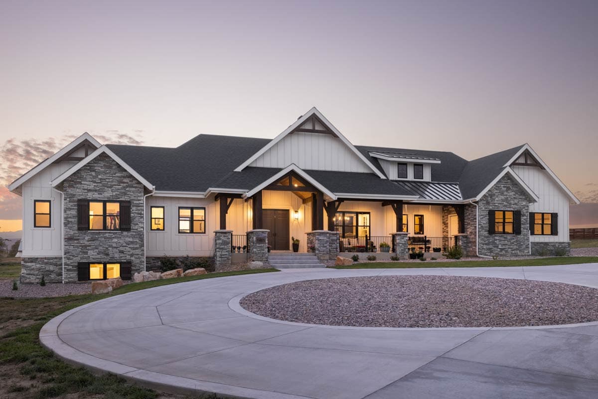 House plan exterior. Modern farmhouse style with stone accents, gabled roof, and covered porch. Features include dormers and a circular driveway.