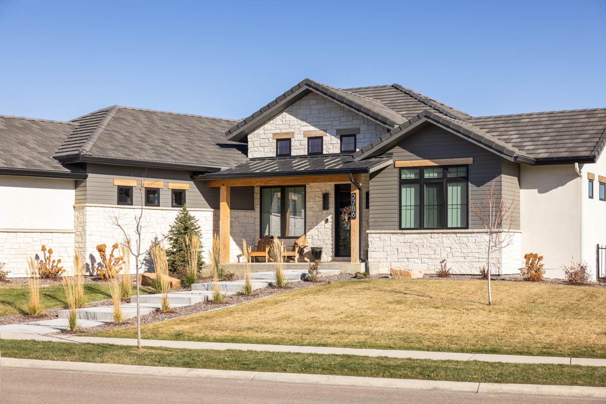 House plan exterior: Ranch style with stone and wood siding, covered porch with timber posts, and multiple gables.