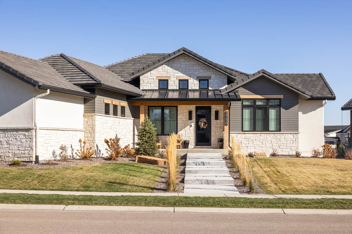 House plan exterior with stone and wood siding, covered entryway, multiple gables, and a dark tiled roof.