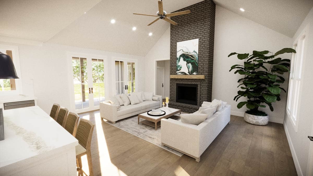 Spacious, modern living room with fireplace, sofas, and large plant. Light-filled space with a vaulted ceiling.