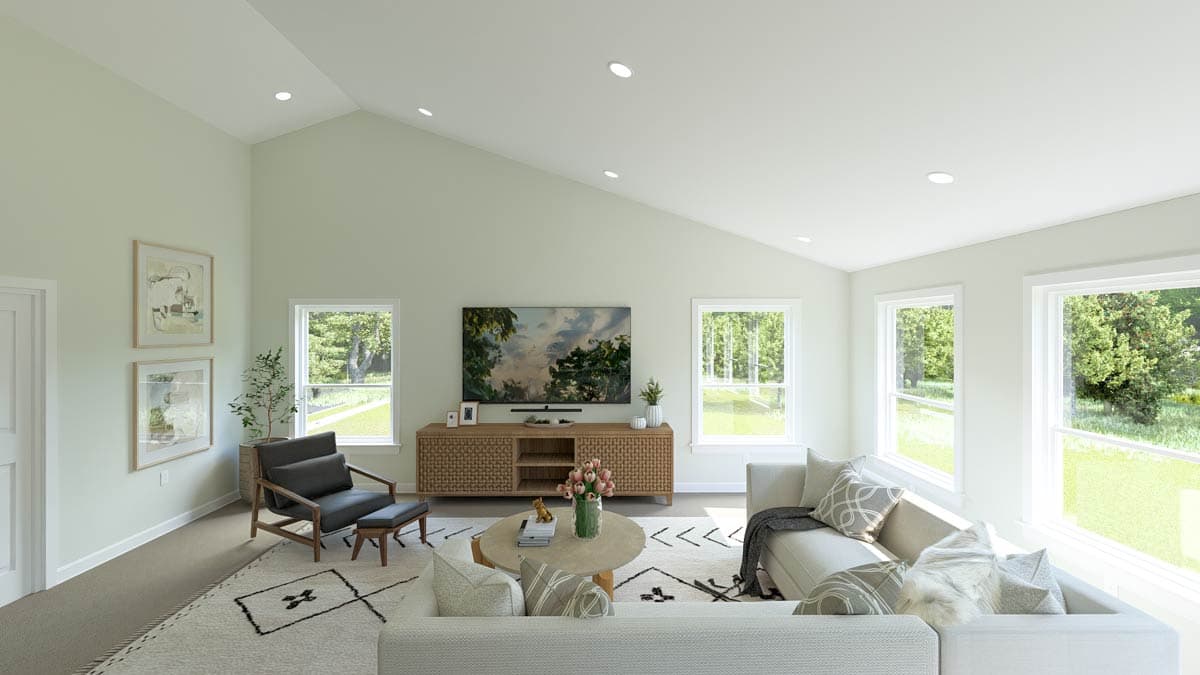 Great room with vaulted ceiling, fireplace, media console, and large windows overlooking greenery.