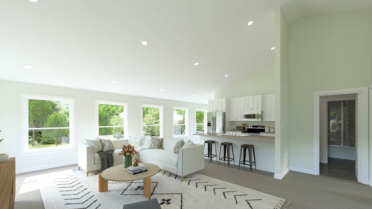 Open concept living area with vaulted ceiling, kitchen island, and multiple large windows.