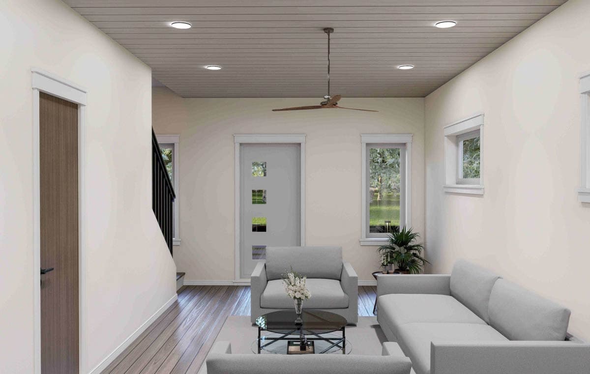 Interior view of a living area with gray sofas, glass coffee table, and wood-look flooring. A modern door and stairs are visible.