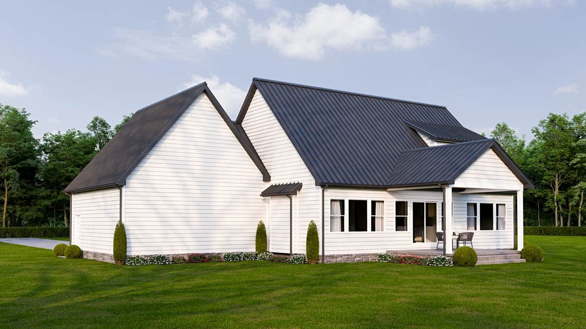 A modern white house with a dark gray roof sits on a green lawn. Trees frame the house, and a porch has a small seating area.