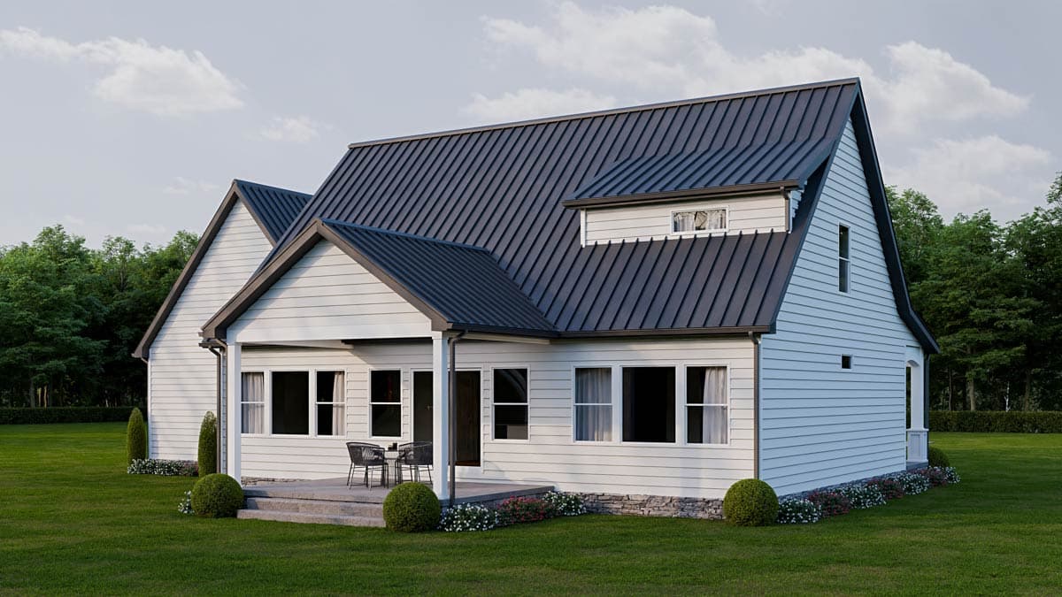 Modern farmhouse with a dark metal roof and white siding, featuring a porch with a seating area, set on a green lawn with a treeline.