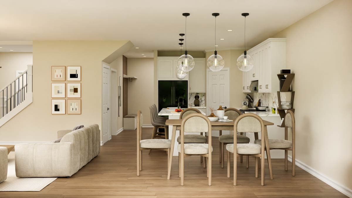 An open-plan living and dining space. A sofa sits near a staircase leading up to an upper level. A dining table and kitchen are in the background.