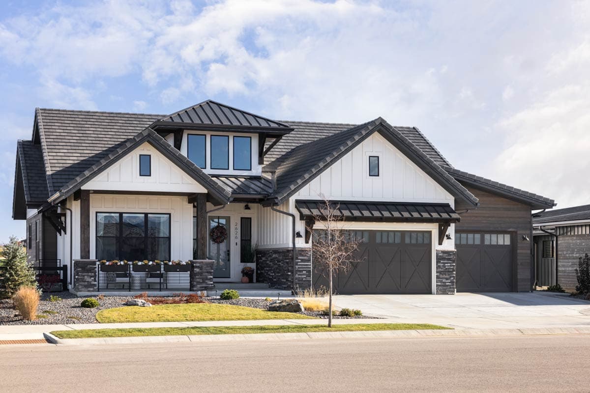 Modern Farmhouse house plan exterior with prominent gables, metal roof accents, stone facade, and a three-car garage.