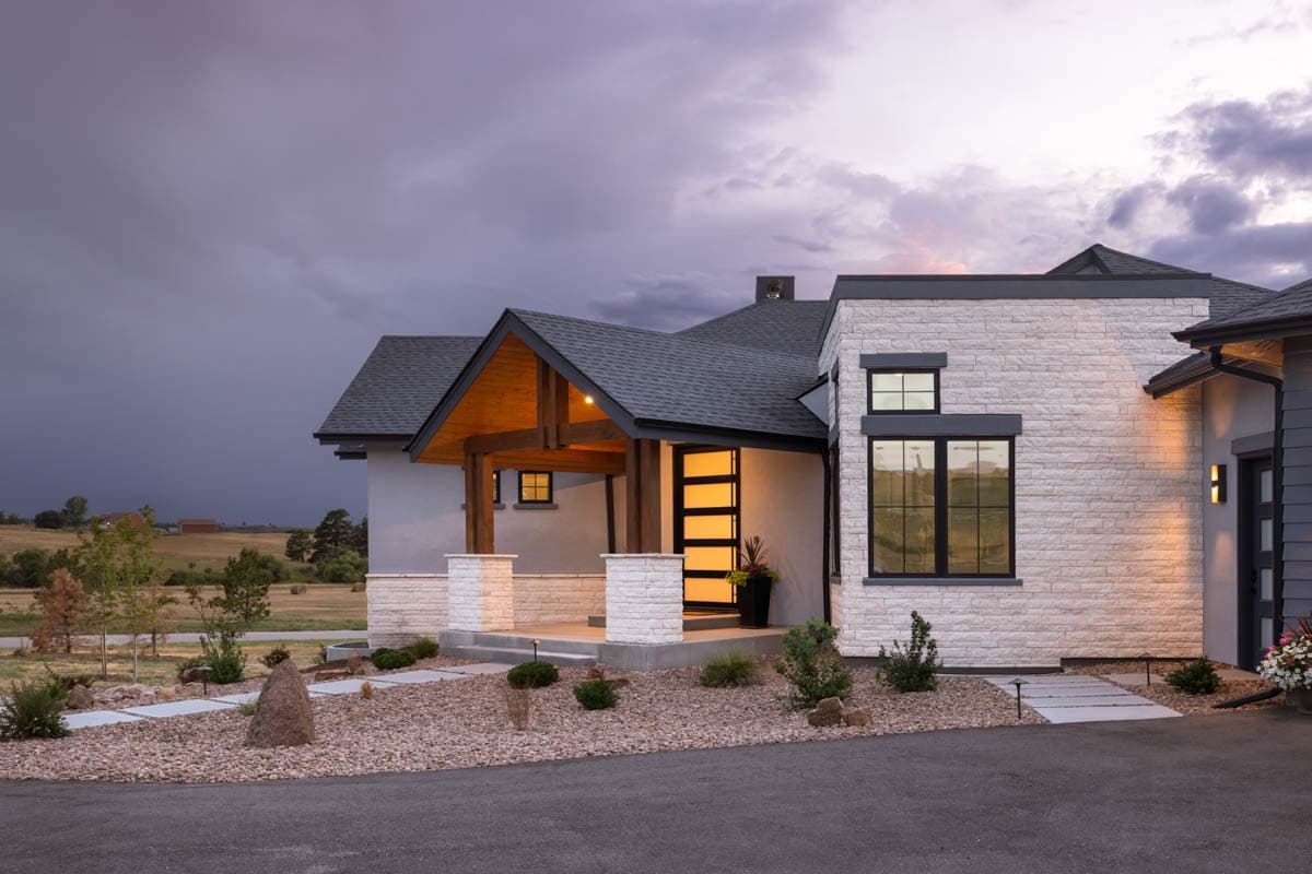 Modern house plan exterior with exposed wood beams on porch, stone facade, and large dark-framed windows.
