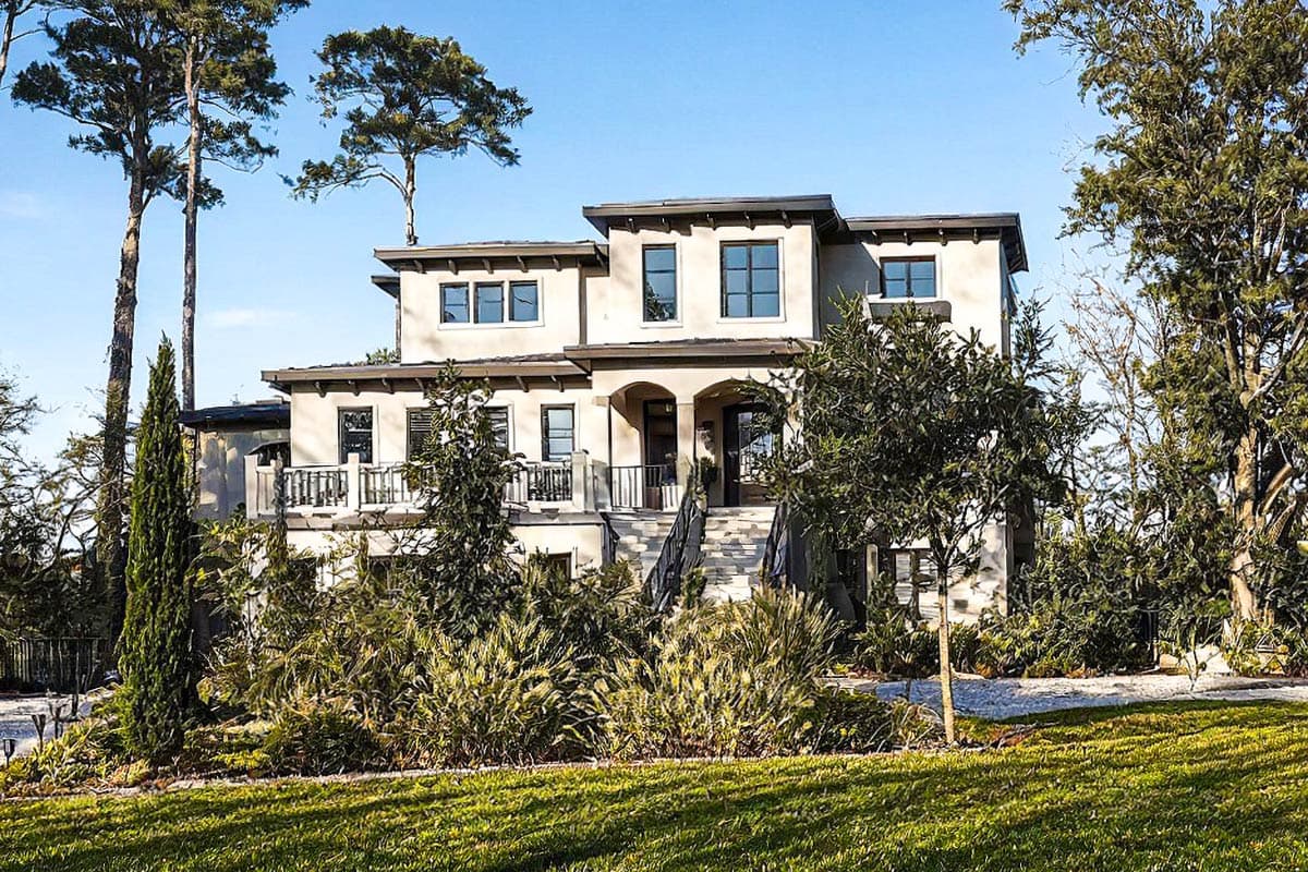 House plan exterior: Modern Mediterranean style, three stories, arched entryway, upper-level balcony, flat roof.