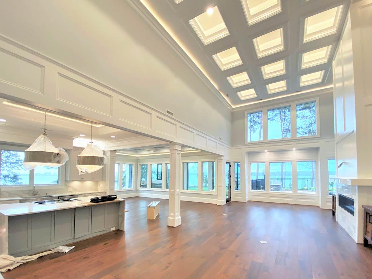 Spacious great room with coffered ceiling, large windows, fireplace, and kitchen island.