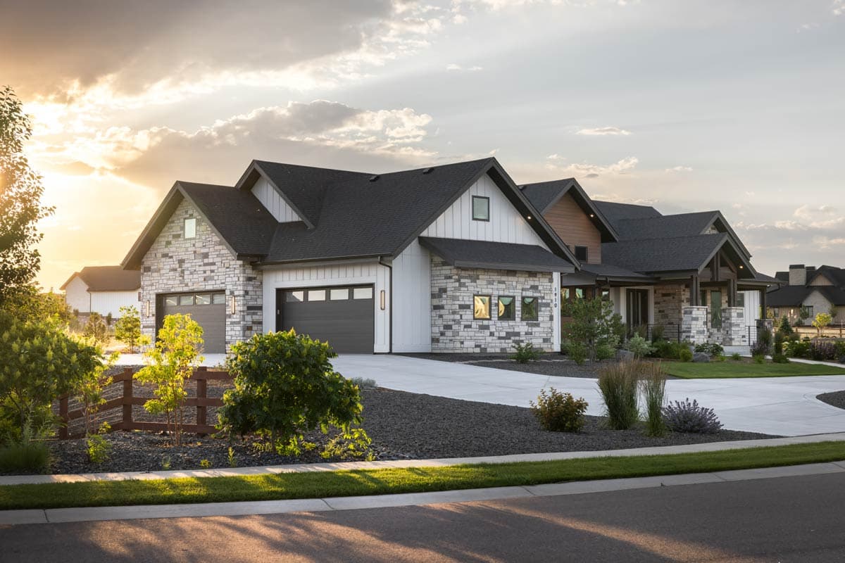 House plan exterior with stone and white siding, multiple gables, and a three-car garage under dark asphalt roofing.