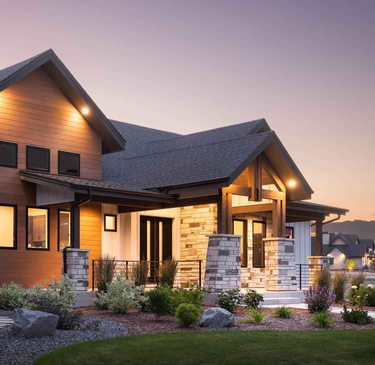Modern house plan exterior with wood siding, stone accents, and exposed timber beams supporting a covered porch.