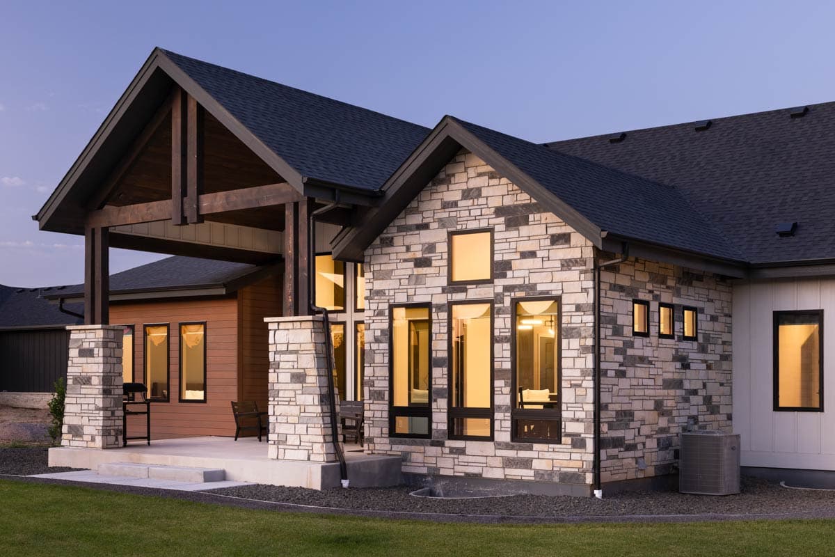 House plan exterior featuring stone facade, covered porch with exposed wood beams, and multiple gables.