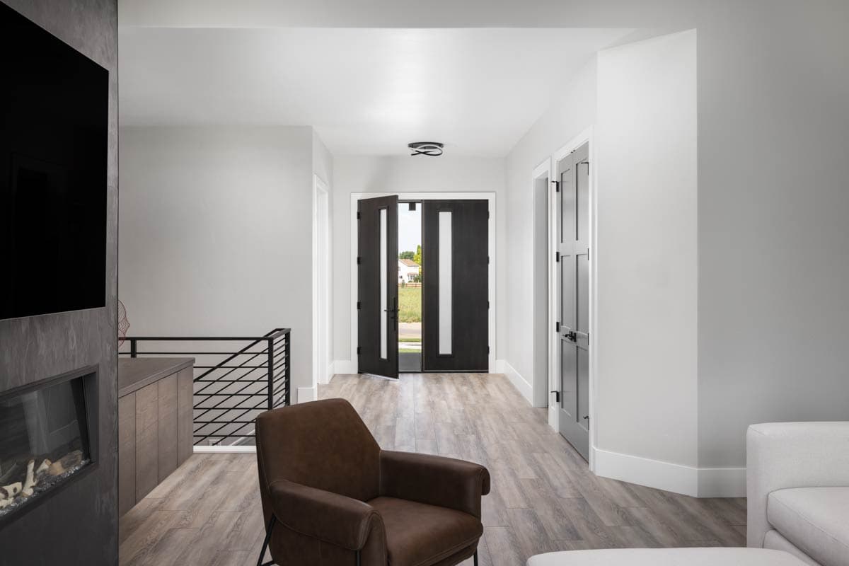 Interior view of a modern entryway with double doors, a linear fireplace, and a view of the exterior.