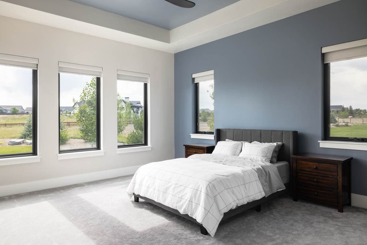 Bedroom with large windows, a king bed with plaid bedding, and a tray ceiling.