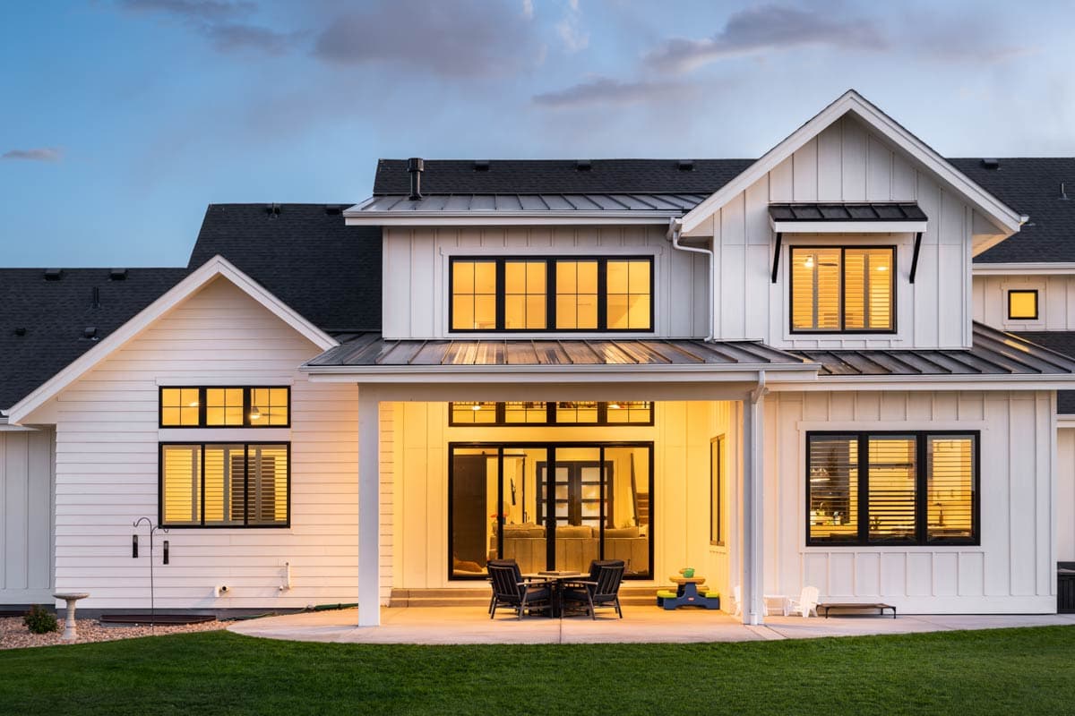 Modern Farmhouse house plan exterior with white siding, multiple gables, metal roof, and covered patio.