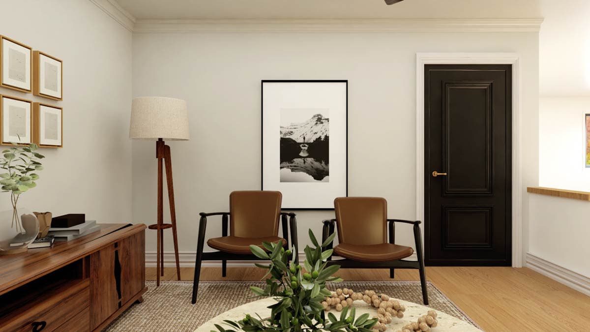 Interior view of a room with a dark paneled door, two brown leather chairs, a wooden console table, and artwork.