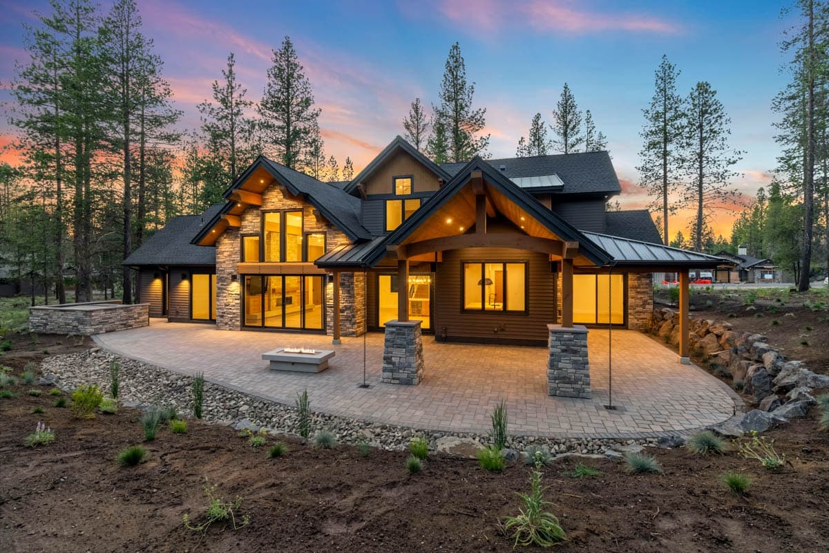 Modern Mountain home exterior with stone and wood accents, large windows, covered porch, and stone patio.