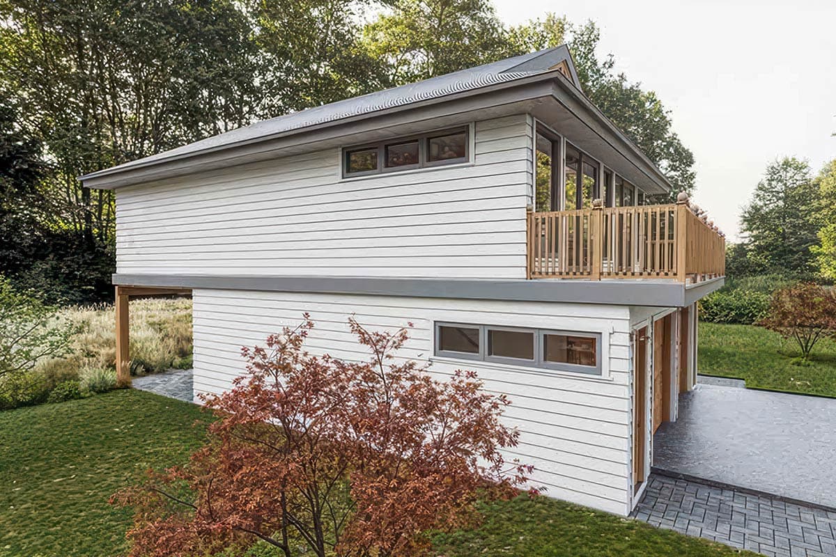 Modern house plan exterior with white horizontal siding, large windows, a cantilevered upper level with a wooden deck, and a shed roof.