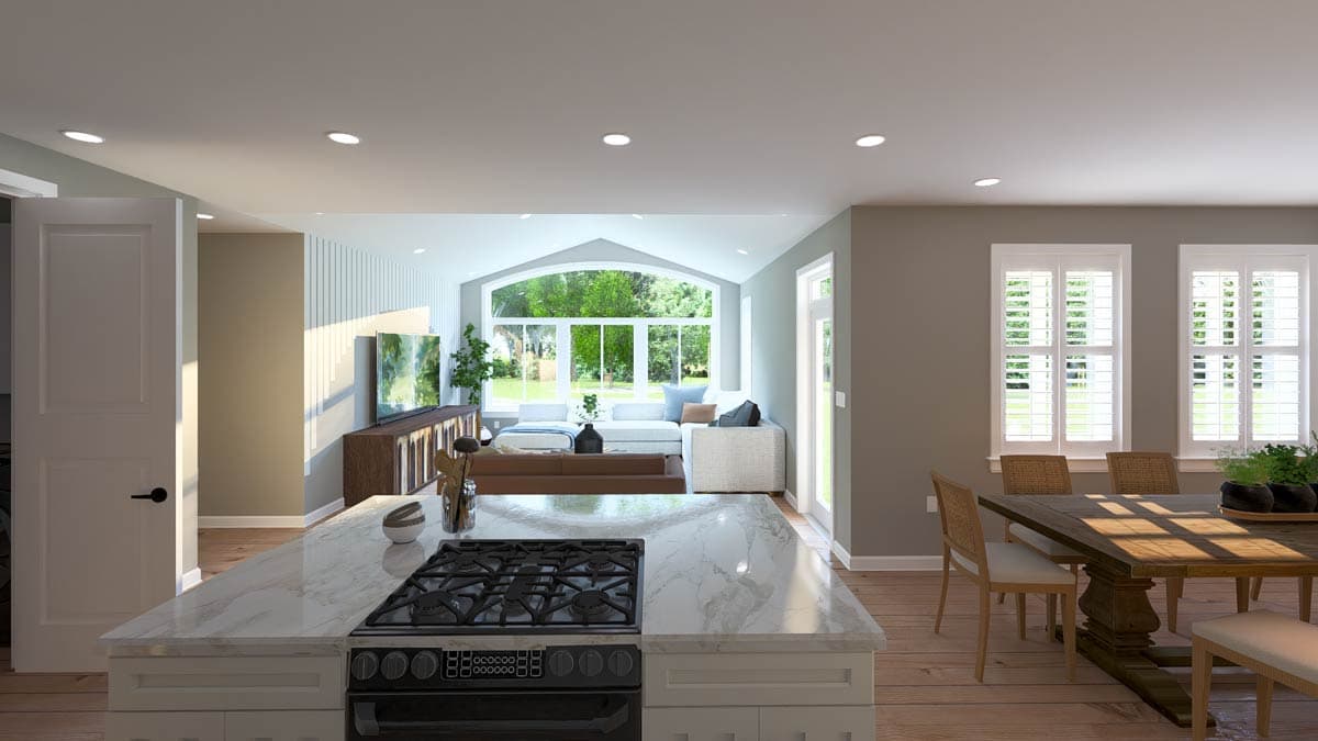 Open-concept interior: kitchen island with gas range, dining area, and living room with large arched window.