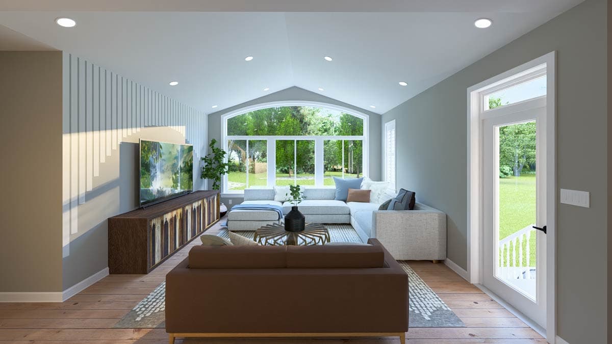 Great room with a large sectional sofa, media console, and arched window wall with multiple panes.
