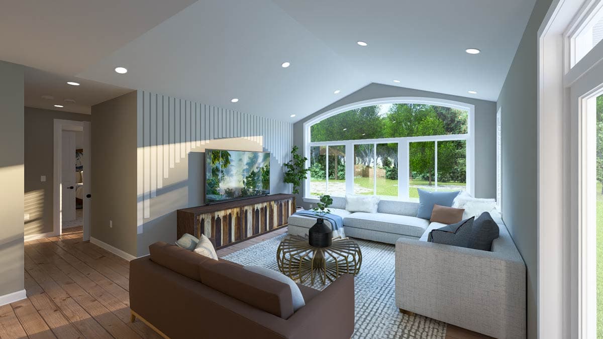 Living room with vaulted ceiling, large arched window, sectional sofa, and entertainment console with wall-mounted television.