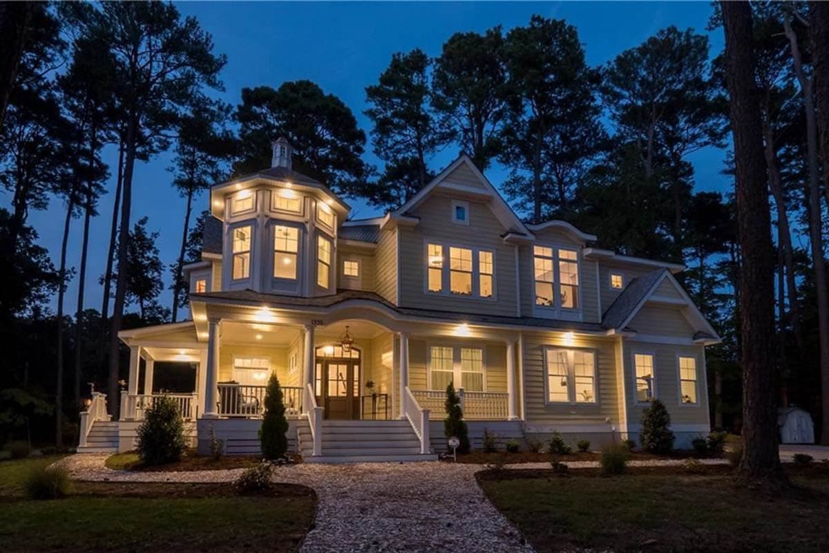 House plan exterior. Two-story Victorian style home with wraparound porch, turret with multi-paned windows, and multiple gables.