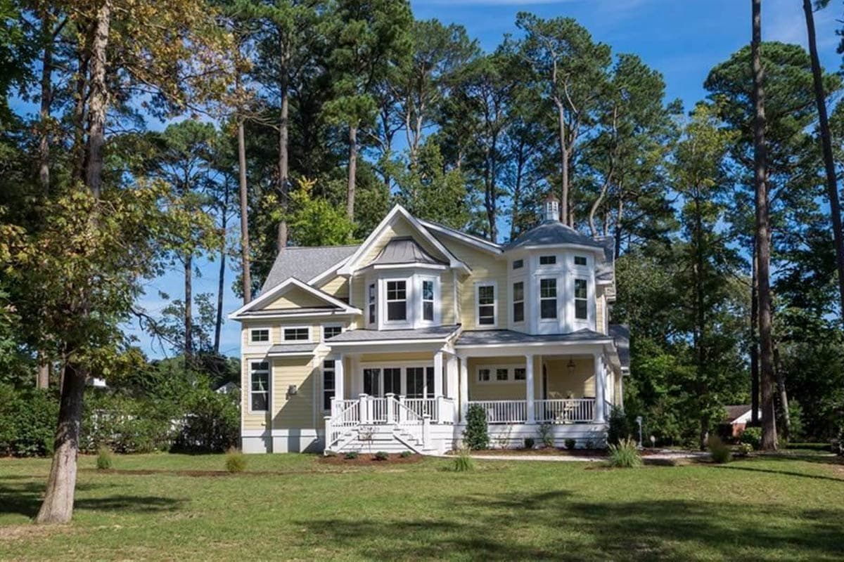 Two-story house plan exterior with a wrap-around porch, bay windows, and a turret-style dormer.