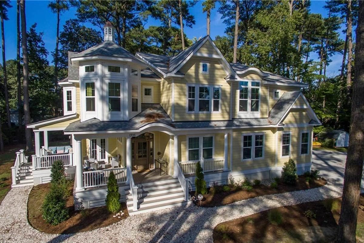 House plan exterior: Two-story home with wraparound porch, bay window, and multi-level gables.