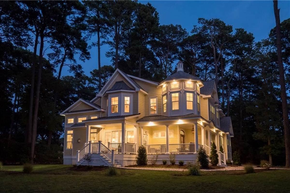 House plan exterior: two-story home with wrap-around porch, prominent bay window, and turret with cupola.