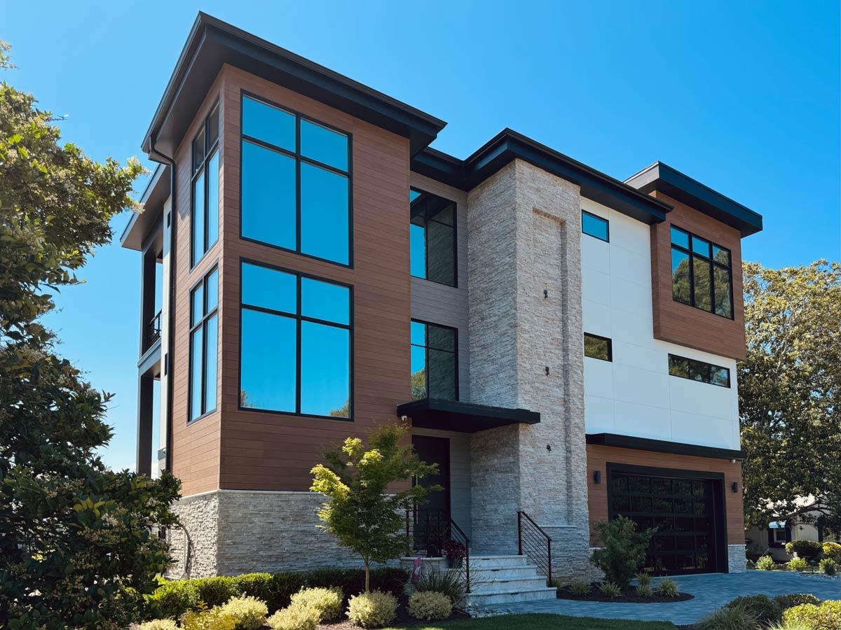 Modern house plan exterior with stacked stone accents, wood siding, large windows, and a glass garage door.