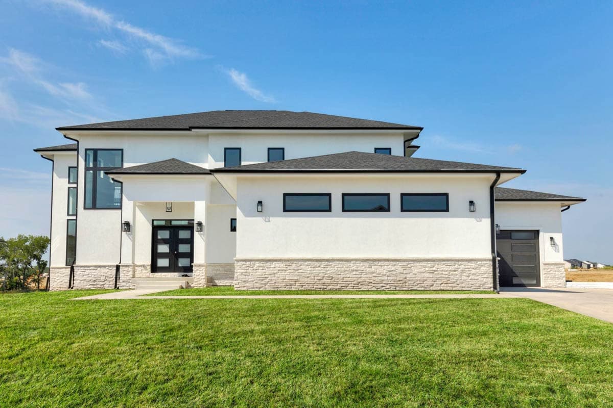 Modern two-story house plan exterior with white stucco, stone base, black-framed windows, covered entry, and attached garage.