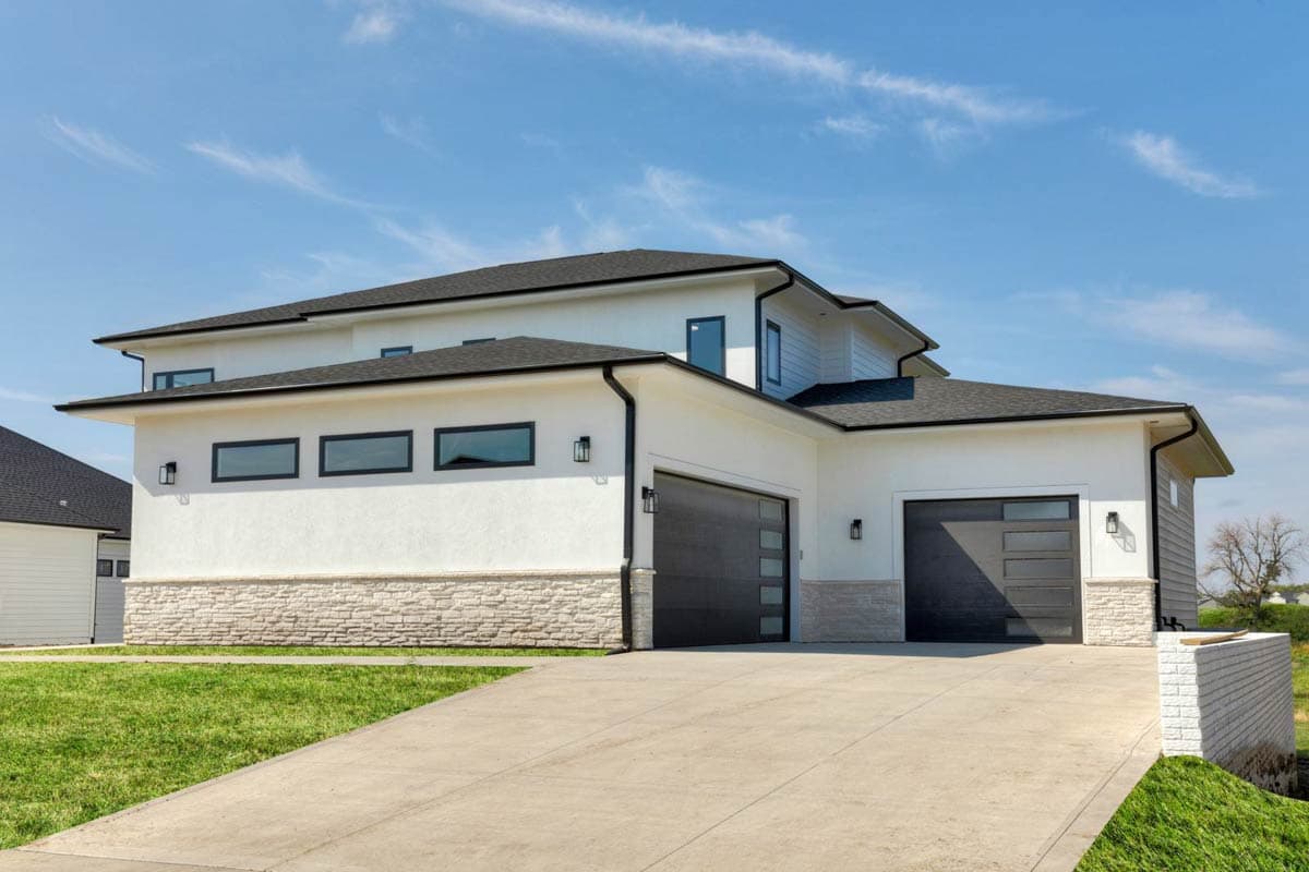 Modern house plan exterior with stucco, stone base, two-car garage, and horizontal windows.